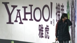 FILE - A woman walks past a Yahoo billboard in a Beijing subway station, March 17, 2006. Yahoo Inc. withdrew from the China market Nov. 1, 2021, because of an increasingly challenging business and legal environment.