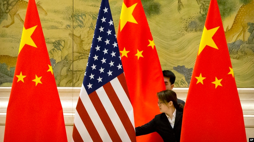 FILE - Chinese staffers adjust U.S. and Chinese flags before a session of negotiations between U.S. and Chinese trade representatives, at the Diaoyutai State Guesthouse, in Beijing, China, Feb. 14, 2019.