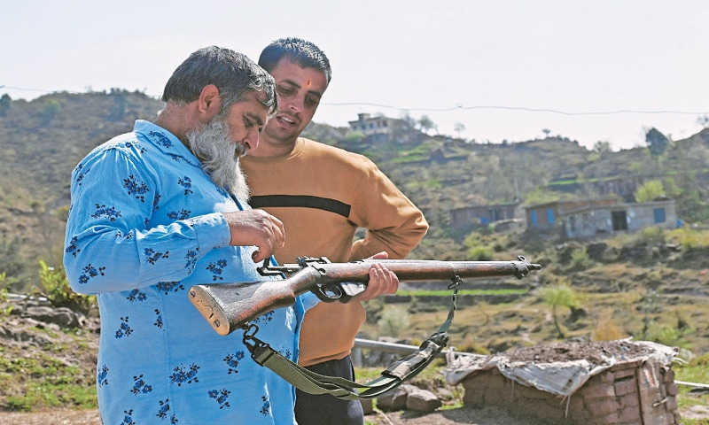 Abdul Qayoom, a retired Indian soldier, gives tips to civil servant Sanjeet Kumar (right) about using a bolt-action rifle in Dhangri village of India-held Kashmir.—AFP