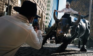 A man sits on the Wall Street bull near the New York stock exchange, which has continued to surge despite the economic crisis.