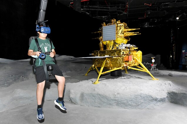 a child wears a vr headset and walks around a fake lunar landing