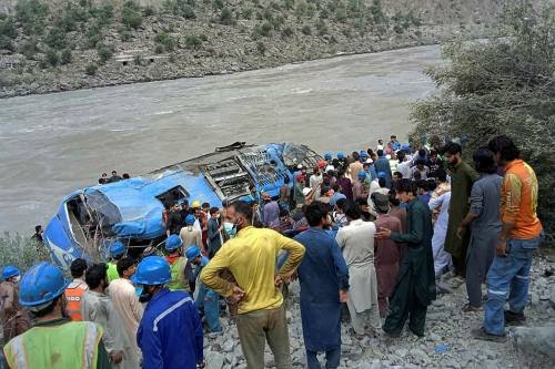 Rescue workers and onlookers gather around a wreck after a bus plunged into a ravine following a bomb explosion, which killed 12 people including 9 Chinese workers, in Kohistan district of Khyber Pakhtunkhwa province on July 14, 2021